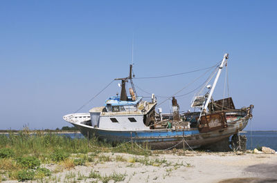 Sailboat moored on sea against clear blue sky