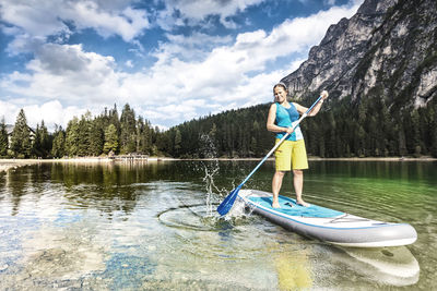 Woman kayaking in lake against sky