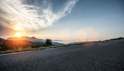 Surface level of empty road against sunset sky