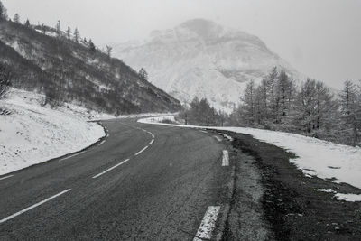 Road by mountains against sky during winter