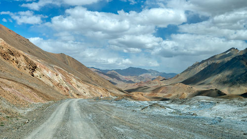 Scenic view of road by mountains against sky