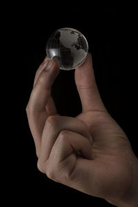 Close-up of hand holding glass against black background