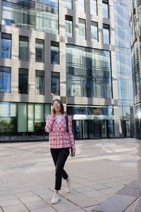 Young woman standing against building