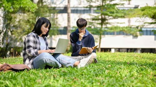 Young man using laptop while sitting on field