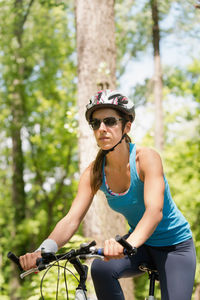 Low angle view of woman riding bicycle in forest