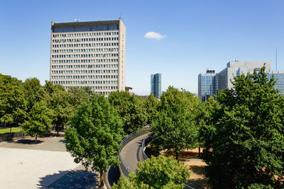 Trees and buildings in city against clear sky