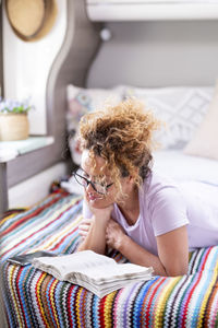 Portrait of young woman using mobile phone while lying on bed at home