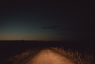 Footpath amidst field against sky at night