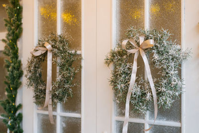 Stylish christmas wreath with a satin bow on the white entrance doors of a country house