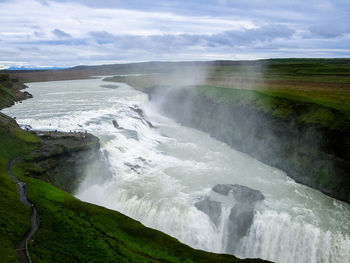 View of waterfall against cloudy sky