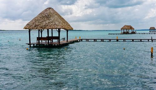 Stilt house in sea against sky