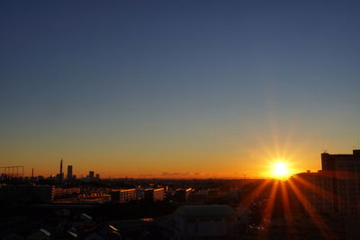 Buildings in city against clear sky during sunset