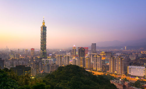 Illuminated buildings in city against sky