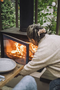 Senior woman putting firewood in fireplace during dinner party