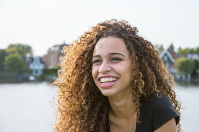 Portrait of smiling young woman against sky