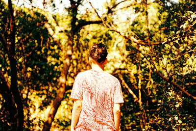 Rear view of woman standing on tree trunk