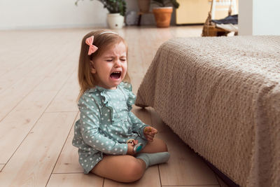 Girl crying sitting on floor at home