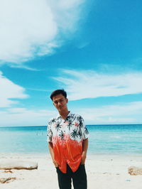 Young man standing at beach against sky