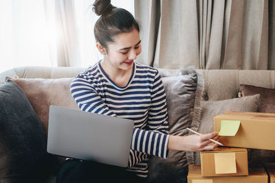 Young man using digital tablet while sitting on sofa at home