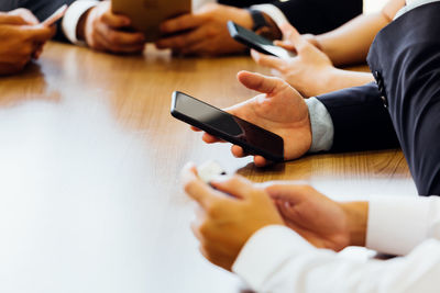 Midsection of man using mobile phone on table