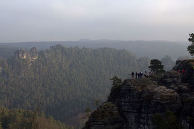 Panoramic view of people on cliff against sky