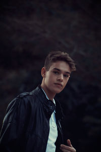 Portrait of teenage boy wearing leather jacket standing outdoors