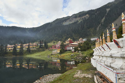 Scenery view of old buildings of tibetan buddhist temples located on shore of tranquil reflecting lake in highland covered with clouds