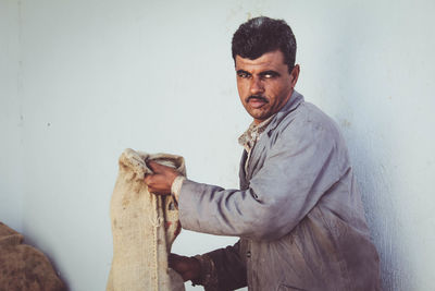 Portrait of smiling young man standing against wall