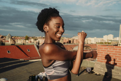 Smiling female stretching on rooftop during sunrise