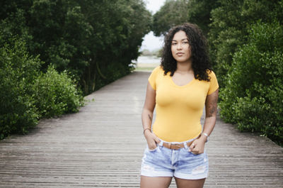 Portrait of young woman standing against yellow plants