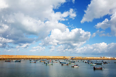 Boats moored on sea against cloudy sky