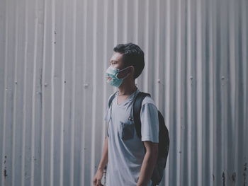 Side view of young man looking away against wall