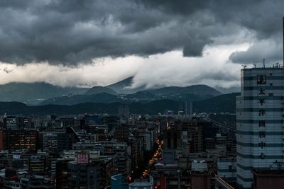 Aerial view of buildings in city against storm clouds