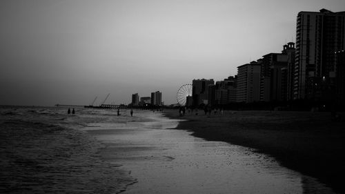 Scenic view of sea shore by city against sky