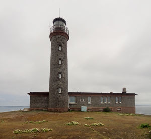 Lighthouse by building against sky