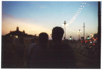 Rear view of people in city against sky