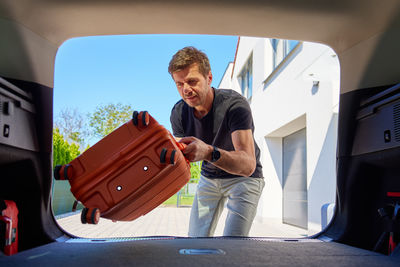 Side view of man standing in car