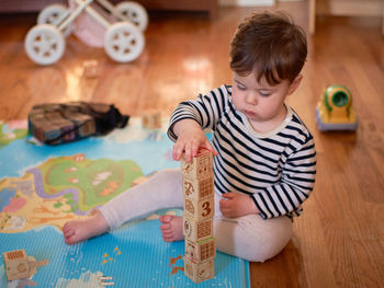 Cute toddler boy makiung a tower from wood blocks