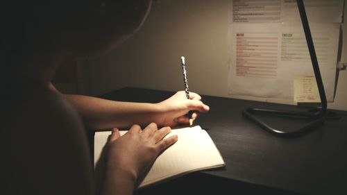 Close-up of boy writing in note pad