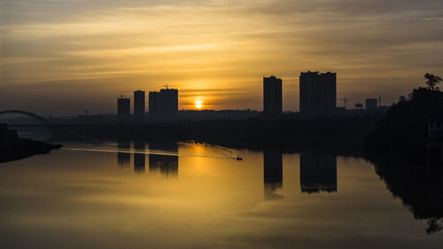 Reflection of cityscape in water during sunset