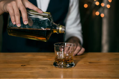 Midsection of man drinking glass on table