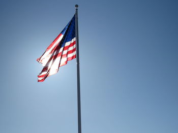 Low angle view of american flag against clear blue sky