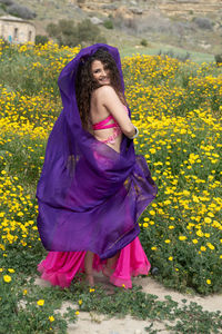 Full length of a beautiful woman standing on yellow flowering plants