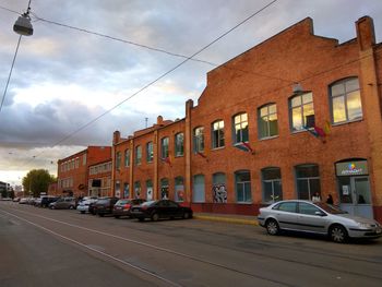 Cars on street in front of buildings against sky