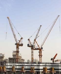 Cranes at construction site against clear sky