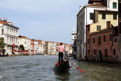 Rear view of man on canal against buildings