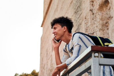 Young man with afro hair is using his smartphone outdoors