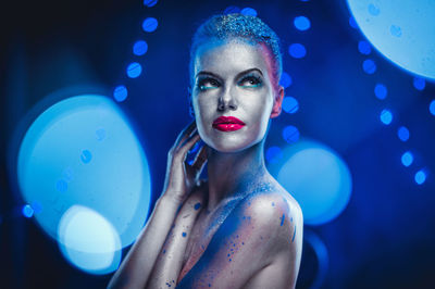 Thoughtful naked woman with glitter against blue background