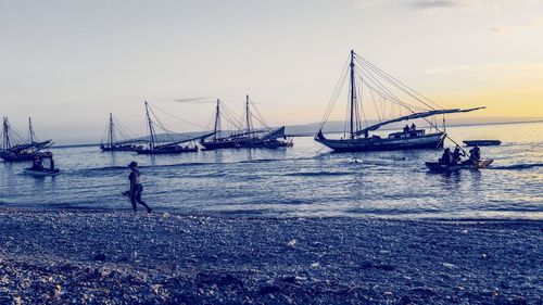 Sailboats in sea against sky during sunset