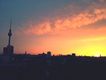 Communications tower in city at sunset